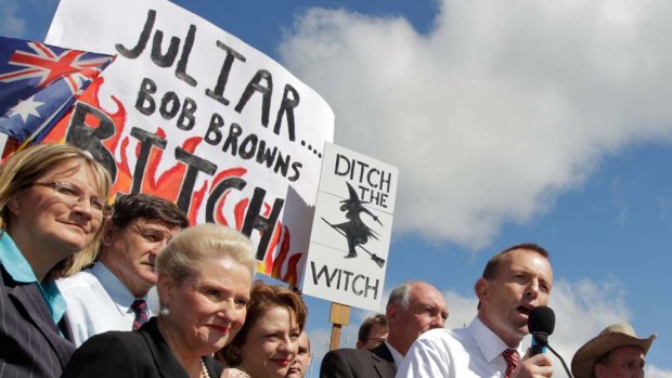 Protesters hold up controversial posters behind Tony Abbott as the Opposition Leader   speaks at the No Carbon Tax rally outside Parliament House in Canberra.