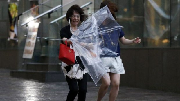 Women struggle with strong winds and rain caused by Typhoon Halong in Tokyo on Sunday.