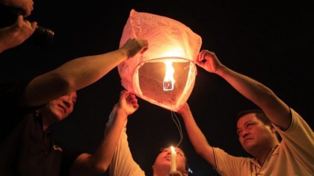 People prepare to release a sky lantern during a candlelight vigil for passengers aboard a missing Malaysia Airlines plane in Kuala Lumpur, Malaysia.