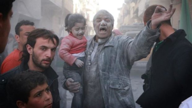 Victims of war: Covered in dust, a Syrian man holds a crying girl after an air strike by government forces on the Sahour neighbourhood of Aleppo.