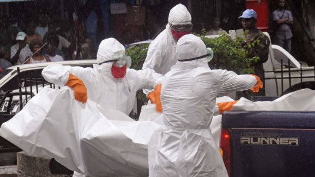 Health workers load the body of an amputee suspected of dying from the Ebola virus on the back of a truck, in a busy street in Monrovia, Liberia.