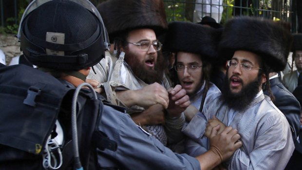 Israeli police officer pushes ultra-Orthodox Jews during the car park protest in Jerusalem.