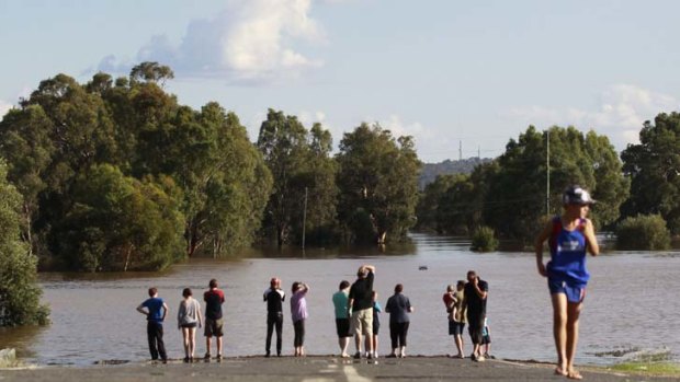 Underwater ... local residents look at a road submerged in flood waters near Wagga Wagga.