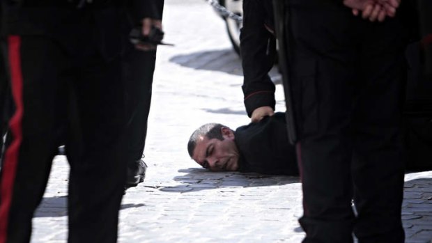 A man believed to be the assailant is detained by police after the shootin in Rome on Sunday.