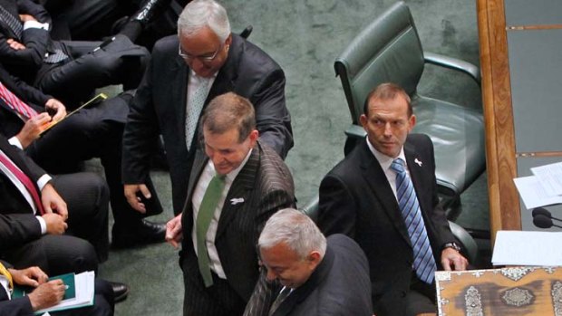 Watchful ... Peter Slipper passes Opposition Leader Tony Abbott on his way to his new seat.