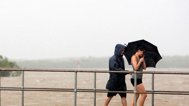 Maroochydore residents walk in torrential rain across the rising Maroochy River on January 11, 201.