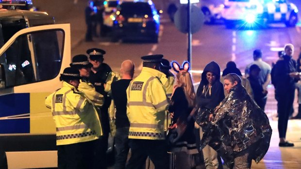 Emergency services personnel speak to people outside Manchester Arena after an explosion.