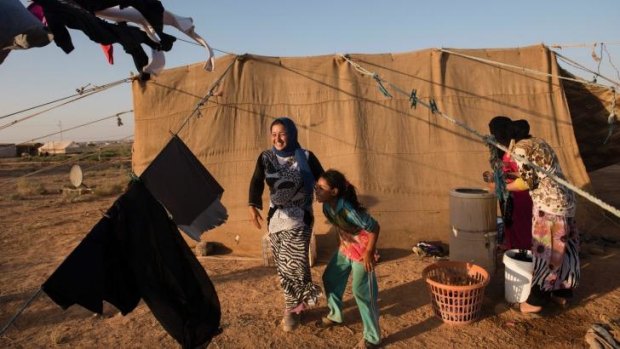Jazia, 15, a Syrian refugee from Hama, laughs with her younger sister as she washes clothes outside of her family’s tent near the Zaatari camp.