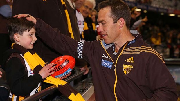 Hawks coach Alastair Clarkson autographs a ball for a young fan after the win over St Kilda.