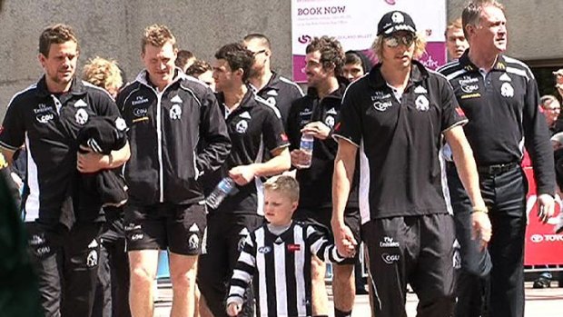 Collingwood players and staff take part in the parade.