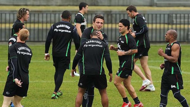 Here you go ... Sam Burgess, centre, lends a helping hand at training yesterday.