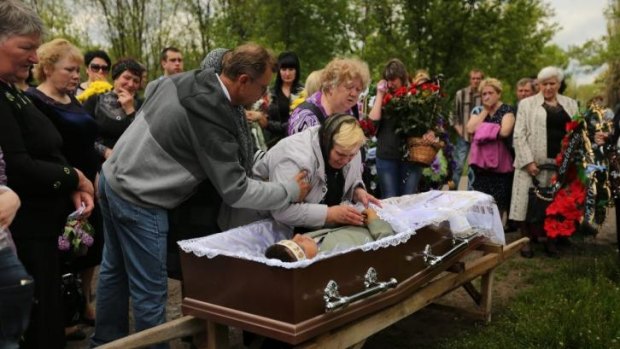 The mother of 39-year-old miner Vadim Hudich embraces her son  during his funeral.