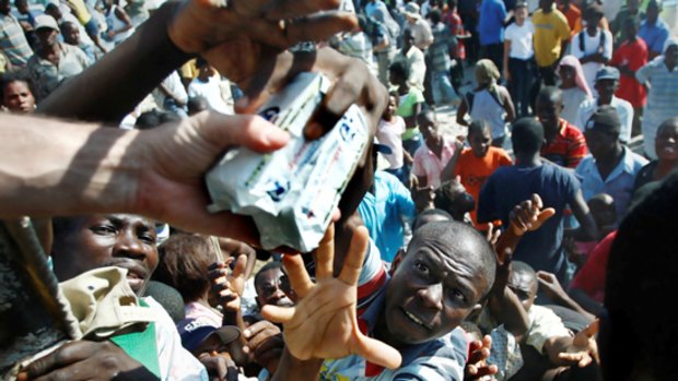 Haitians scramble for aid being issued from the back of a truck in Petionville.