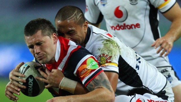 Shaun Kenny-Dowall of the Roosters is tackled by the Warriors' defence.