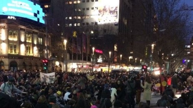Hundreds of protesters block the intersection of Flinders and Swanston streets.