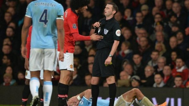 Michael Oliver talks to Marouane Fellaini after an incident with Pablo Zabaleta (prone).