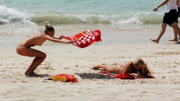 Topless tourists sunbathe on a beach in Sanya.