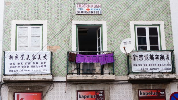 Chinese language signs sit on the balconies of residential properties near Martim Moniz square in Lisbon, Portugal.