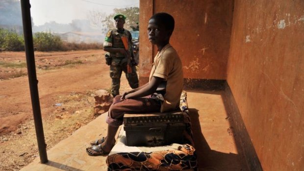 Displaced: A boy sits on the only family belongings left after an attack by Christian militias, as a member of the African Union peacekeeping force stands guard.