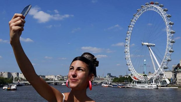 A tourist takes a snap of herself at the London Eye. It may be expensive, unfriendly and dirty, but travellers still rate London as the best city in the world.