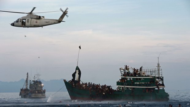 Rohingya swimming to collect food supplies dropped by a Thai army helicopter.