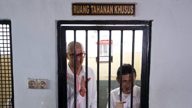 Canadian teacher Neil Bantleman (left) and Indonesian teaching assistant Ferdinand Tjiong wave to students as they wait inside a holding cell before their trial in April. 
