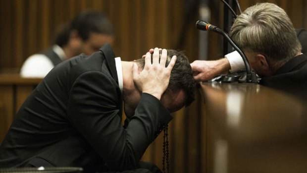 Hard to hear: A member of his legal team reaches out to Oscar Pistorius as he covers his ears with his hands while a witness gives testimony.