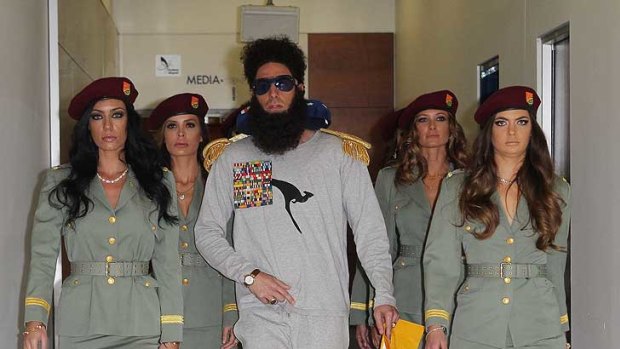 On parade in pyjamas ... Sacha Baron Cohen arrives in Qantas pyjamas and female guards at Sydney Airport.