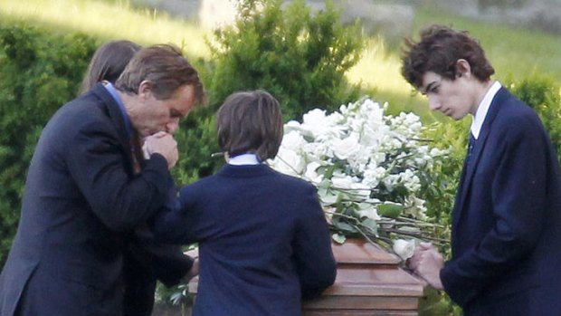 Robert F. Kennedy jnr, left, kneels with his children at the casket of Mary Kennedy, in St Francis Xavier Cemetery in Centerville, Massachusetts.