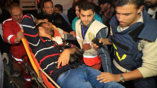 Palestinian medical workers wheel a wounded local journalist on a stretcher to Al-Shifa hospital in Gaza City.