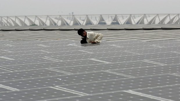 An Indian worker cleans solar panels on top of the new Thyagraj Stadium in New Delhi.