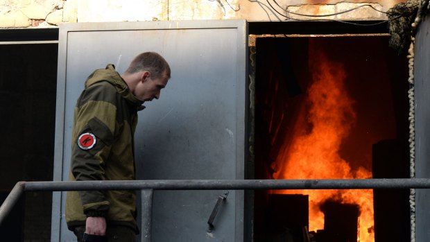 A pro-Russian separatist inspects a fire in a cardboard factory after shelling in Donetsk.