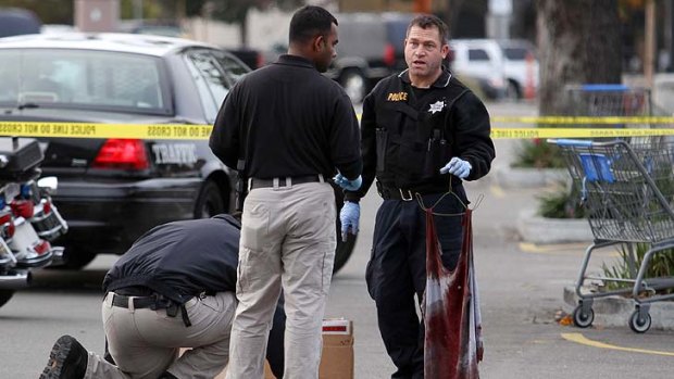A police officer holds a bloody shirt as evidence is gathered at the scene of a shooting at Wal-Mart in California.