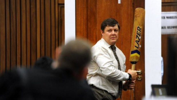 Forensic investigator Johannes Vermeulen demonstrates on a mock-up toilet cubicle how the door could have been broken down by Oscar Pistorius with the cricket bat.