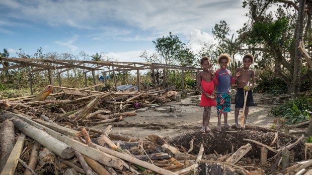 Children near the remains of a local community centre in Port Vila, destroyed in the cyclone.