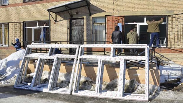 Employees try to fix windows of a maternity ward which was damaged by a shockwave from a meteorite.