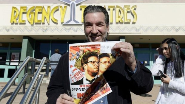 Dennis Lavalle with a ticket and a poster for <em>The Interview</em> at a Christmas Day screening.