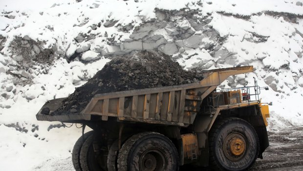 A dump truck transports coal along a snow covered road in Russia.