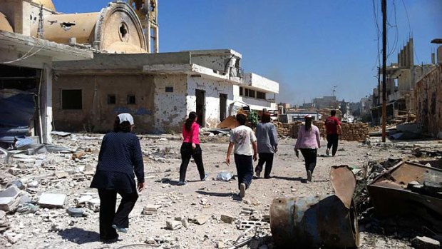 Human tragedy: People walk past a damaged church in Qusayr. The UN fears Syria's civil war could affect the whole Middle East.