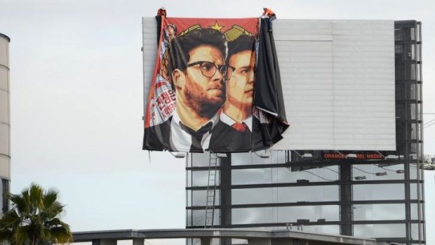 Workers remove a banner poster for <em>The Interview</em> after its cinema release in the US was cancelled.