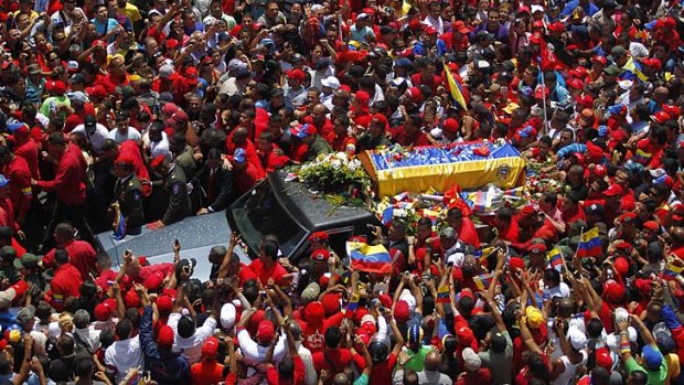 Red tributes: Hugo Chavez's coffin, covered in flags and flowers, is taken to lie in state. ''The struggle goes on!'' his supporters chanted.