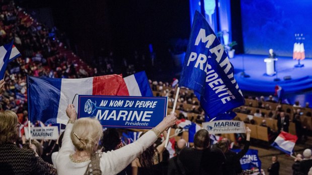 Attendees wave flags and hold signs as Marine Le Pen, leader of the French National Front, speaks in Lyon.