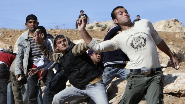Palestinian youths throw stones at Israeli soldiers during a protest in Yatta, near Hebron.