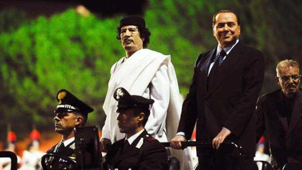 Muammar Gaddafi and Silvio Berlusconi arrive at a ceremony for the Italia-Libya friendship day.