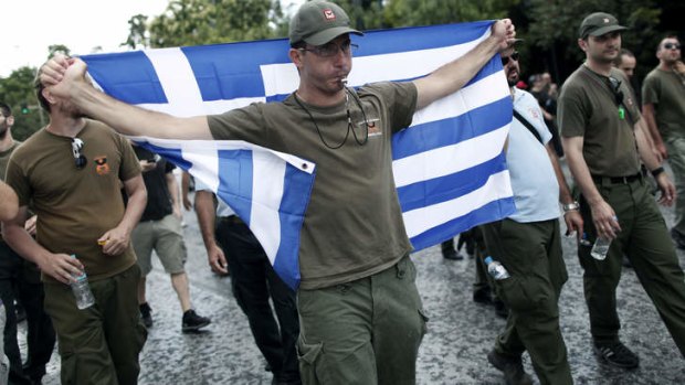 A police officer holds a Greek flag as he takes part in an anti-austerity rally during a 24-hour general strike in Athens on  Tuesday.