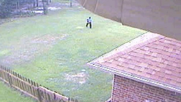 A video surveillance camera image  released by police, shows an unidentified man dressed in what the county sheriff called "ninja garb" heading towards an unlocked utility door in the back of Byrd and Melanie Billings' home in Beulah.