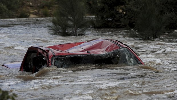A four-wheel-drive vehicle in Paddys River upstream from the Cotter Reserve in the ACT. The driver died after trying to cross the raging torrent.