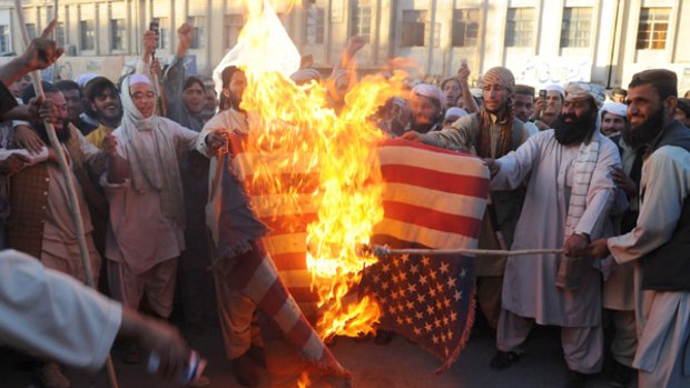 Demonstrators set fire to a US flag.
