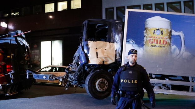 A destroyed truck is pulled away by a service car after it was driven into a department store in Stockholm.
