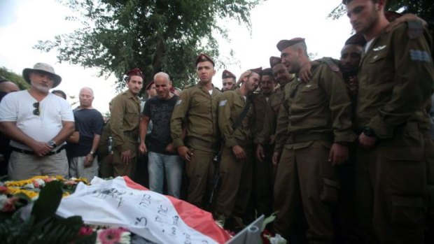 Comrades of Sergeant Banaya Rubel, one of 18 Israeli soldiers killed during Israeli military offensive on the Gaza Strip, mourn above his grave during his funeral in the city of Holon, near Tel Aviv.